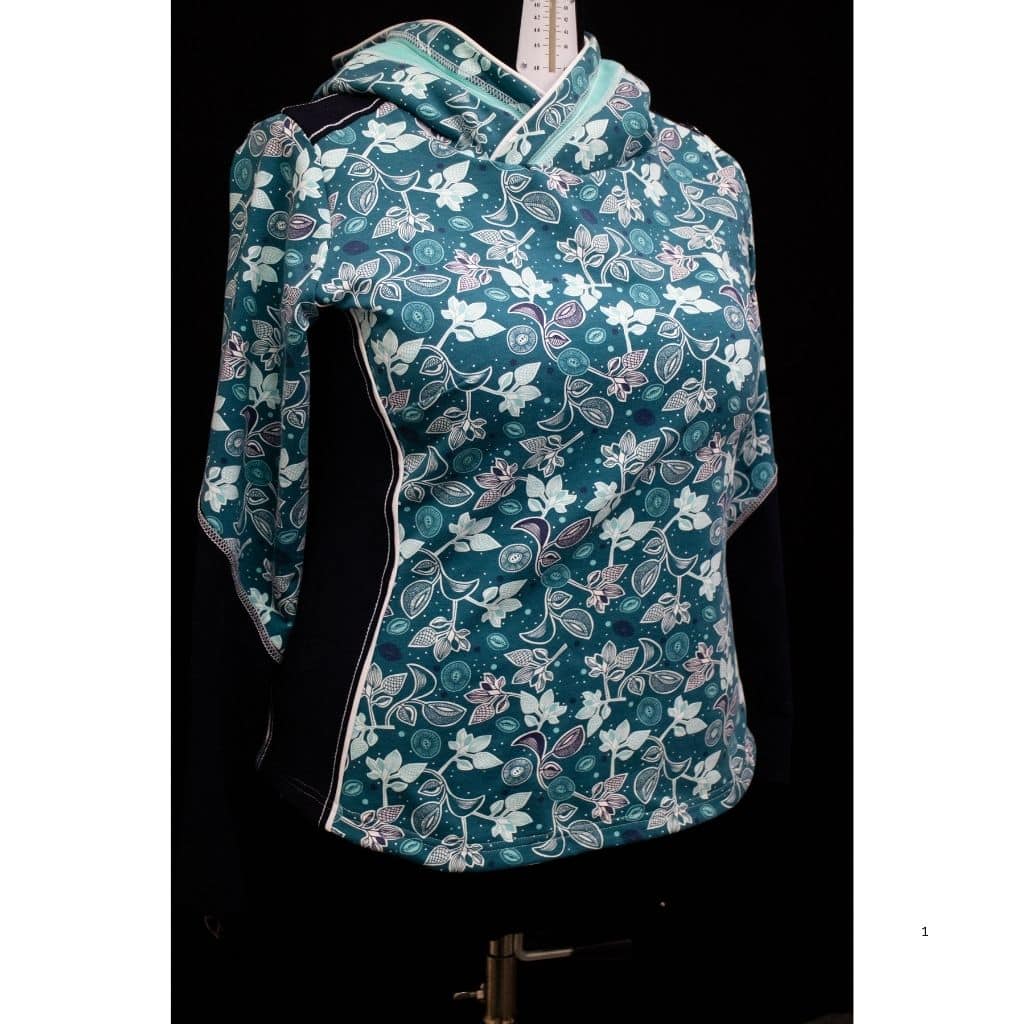Damenhoodie mit floralem Muster in Türkis, Weiß und Violett, dekorativen Teilungsnähten und großer Kapuze auf einer Schneiderpuppe. Vorderansicht