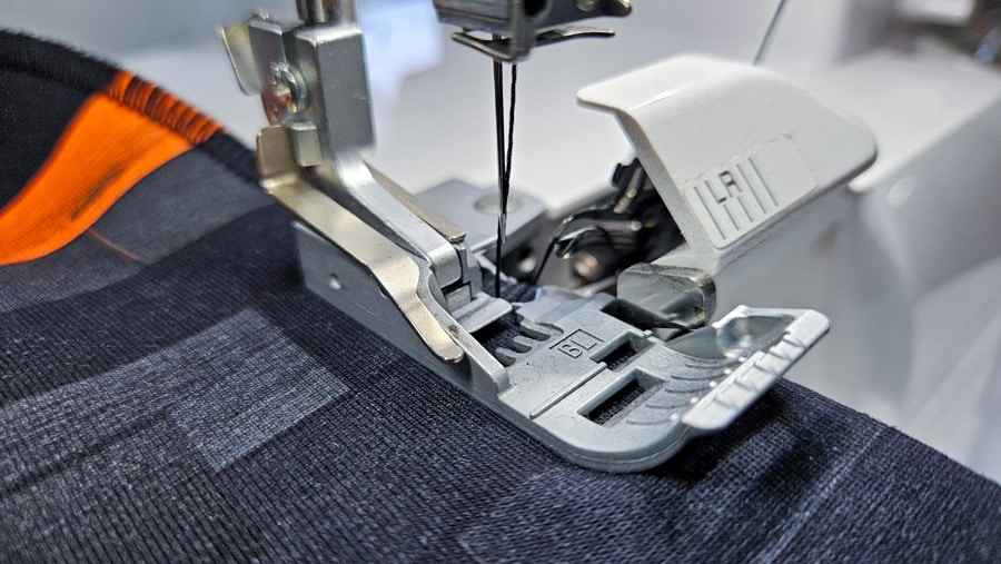 Detailansicht des Nähfußes auf gemustertem Sweatshirtstoff beim Nähen einer Naht.