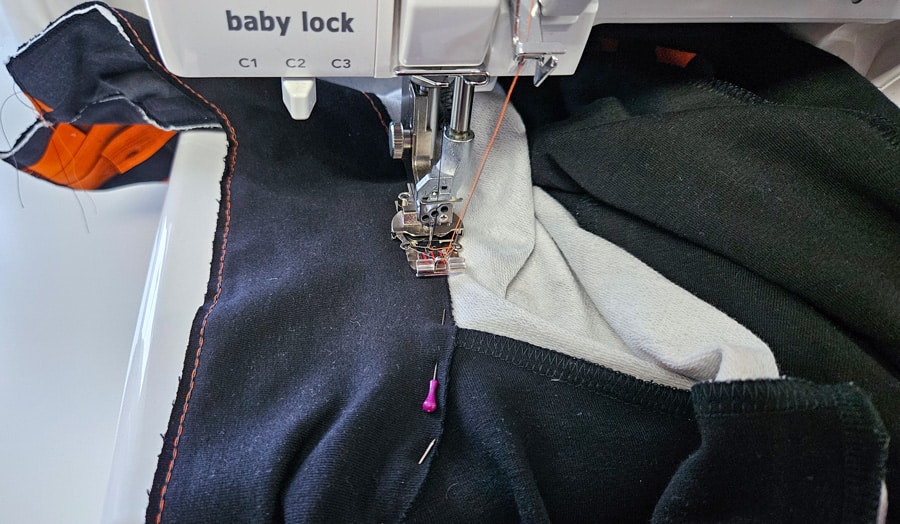 Kragen eines Sweatshirt-Sakkos wird mit Kettstich an den Halsausschnitt genäht.