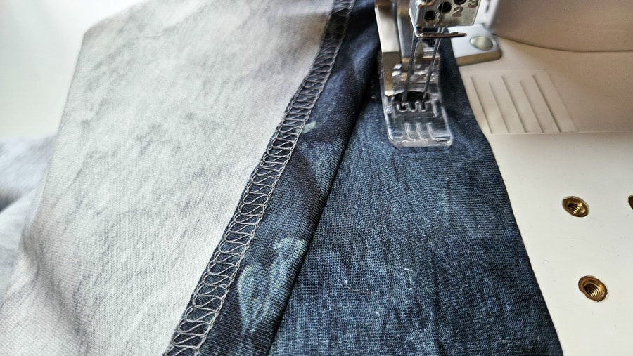 Saum eines Shirts mit Negativapplikation wird mit der Covermaschine sauber gecovert.