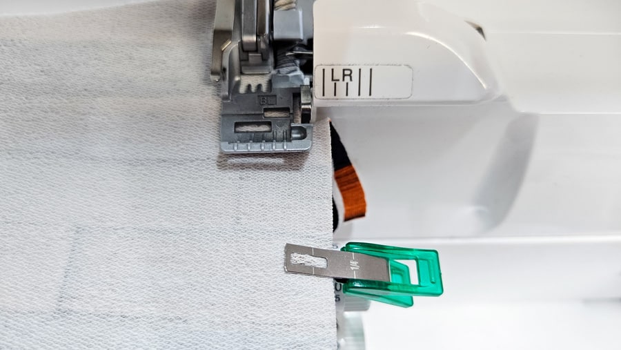Rückenteile eines Sweatshirt-Sakkos werden mit der Overlock zusammengenäht und mit einer Stoffklammer fixiert.