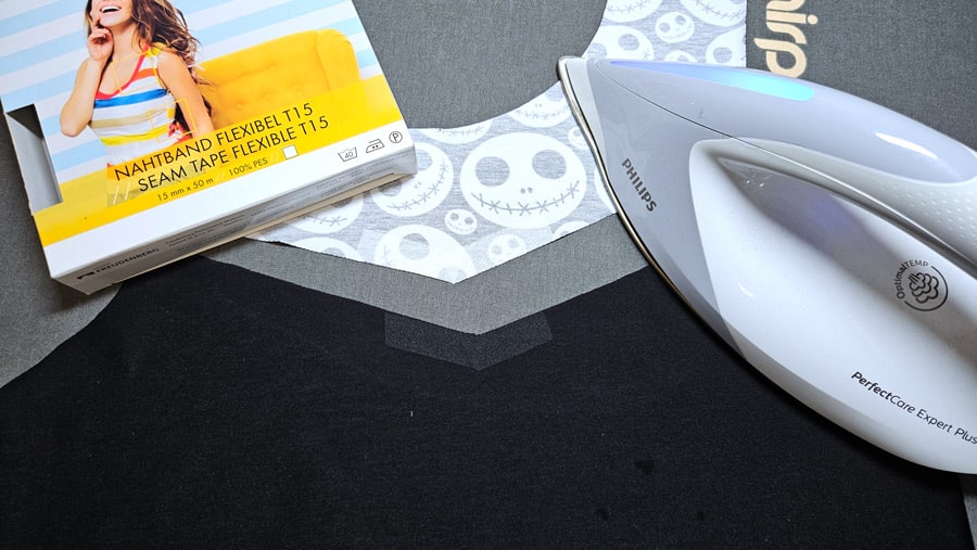 Nahtband wird zur Verstärkung der eckigen Teilung auf ein Shirt-Vorderteil gebügelt.