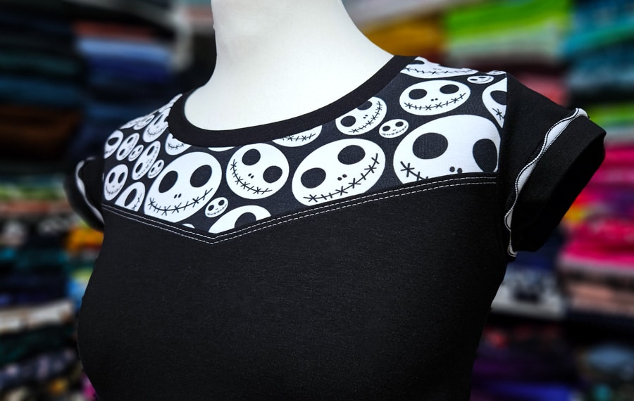 Detailansicht vom fertigen Shirt mit eckiger Teilung, Halsbündchen und kontrastierenden Covernähten.