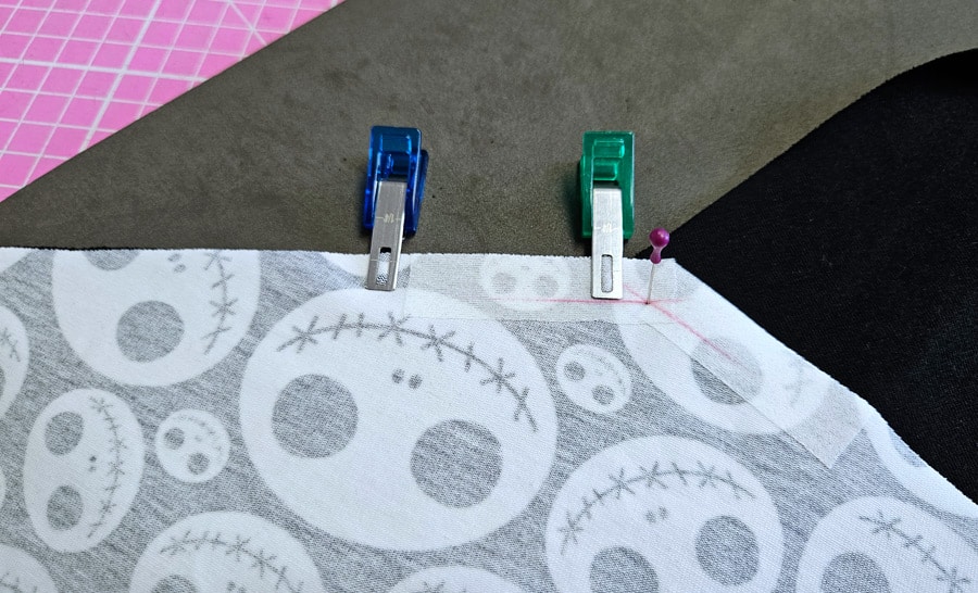 Stoffteile einer eckigen Teilung werden mit Klammern und Stecknadel exakt fixiert.