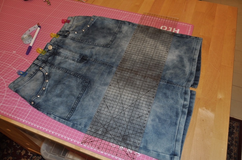 Alter Jeansrock liegt mit Lineal und Rollschneider zum Zuschneiden auf der Schneidematte.