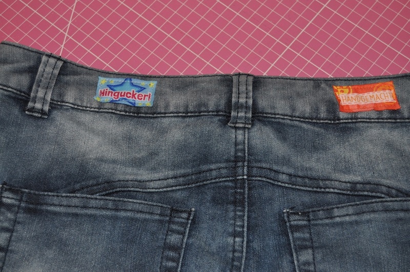 Rückseite des Jeansrockbunds mit Gürtelschlaufen und aufgenähten farbigen Labels.
