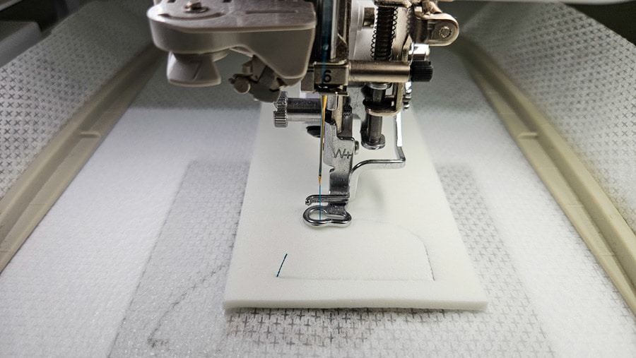 Stickmaschine näht die Konturen des Schriftzugs in den Stickschaum für die Trapunto-Stickerei.