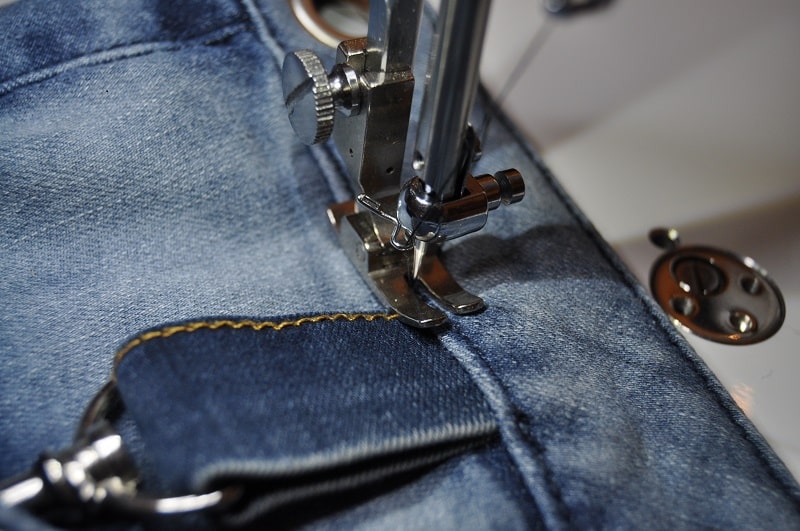 Eine kleine Jeansschlaufe mit Karabiner wird an der Upcycling-Tasche mit der Nähmaschine angenäht.