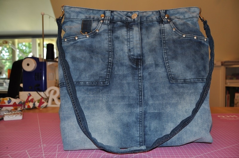 Fertige große Upcycling-Tasche aus einem alten Jeansrock mit langem Schulterträger und erhaltenen Jeanstaschen.