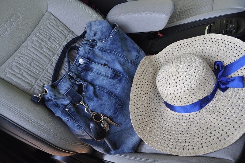 Fertige Upcycling-Tasche aus einem alten Jeansrock liegt zusammen mit einem Strohhut auf dem Autositz.