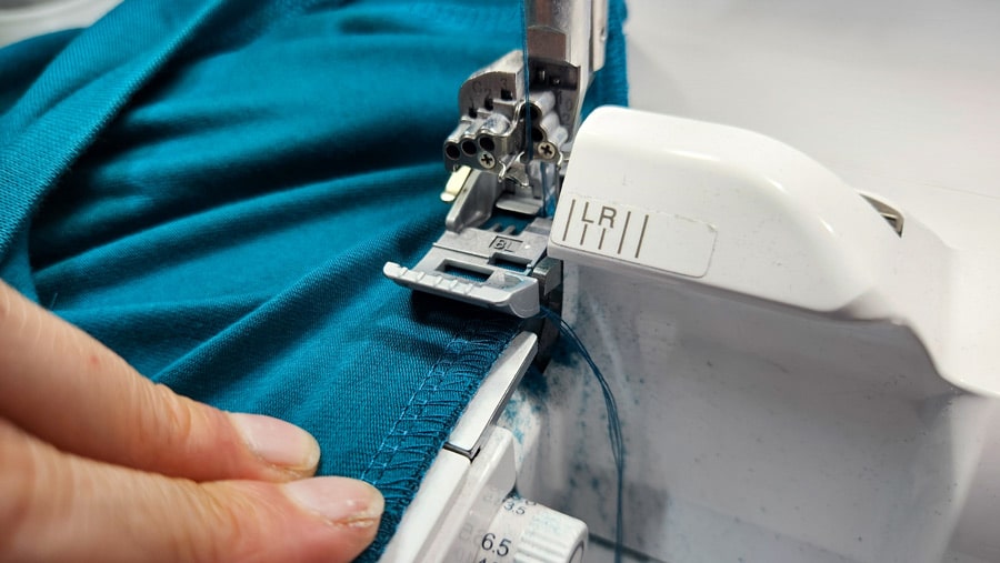 Halsbündchen eines türkisfarbenen Shirts wird mit der Overlock rundgeschlossen angenäht.
