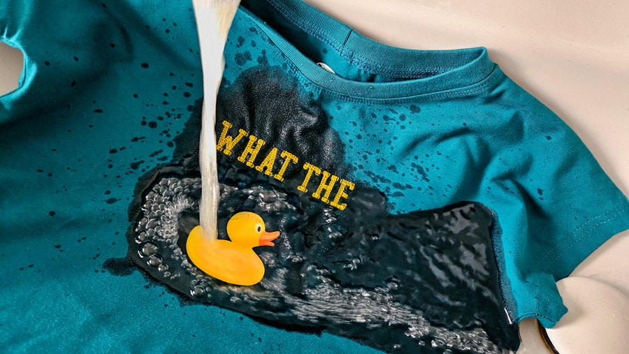 Wasserlöslicher Avalon-Film wird unter fließendem Wasser aus der Trapunto-Stickerei eines Shirts ausgewaschen.