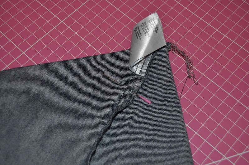 Eine Ecke des Jeansrocks wird diagonal gelegt und für den Taschenboden markiert und gesteckt.