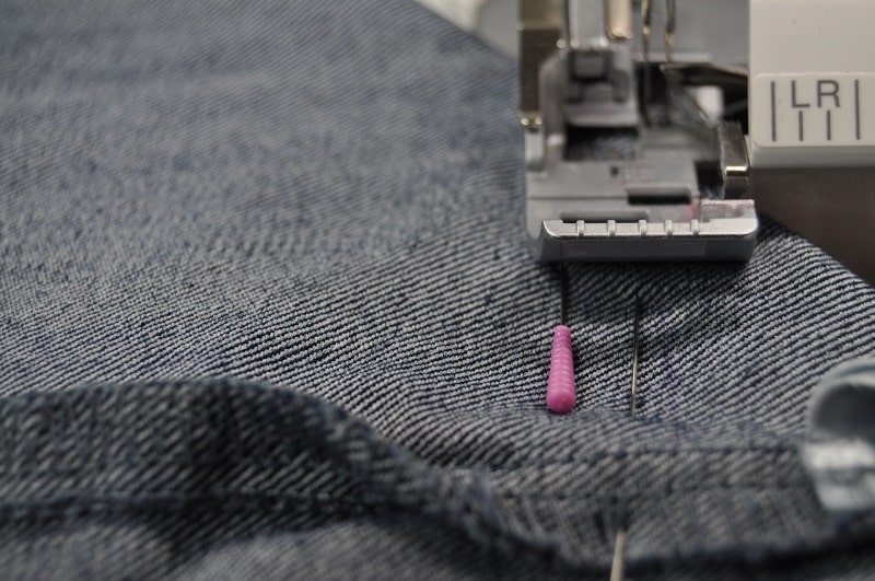 Der Taschenboden der Upcycling-Tasche aus Jeans wird entlang der markierten Linie mit der Overlock genäht.