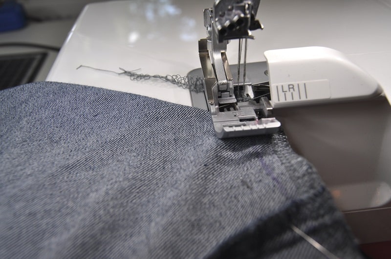 Eine Naht der Jeanstasche wird mit der Overlock korrigiert, damit der Taschenboden gerade wird.